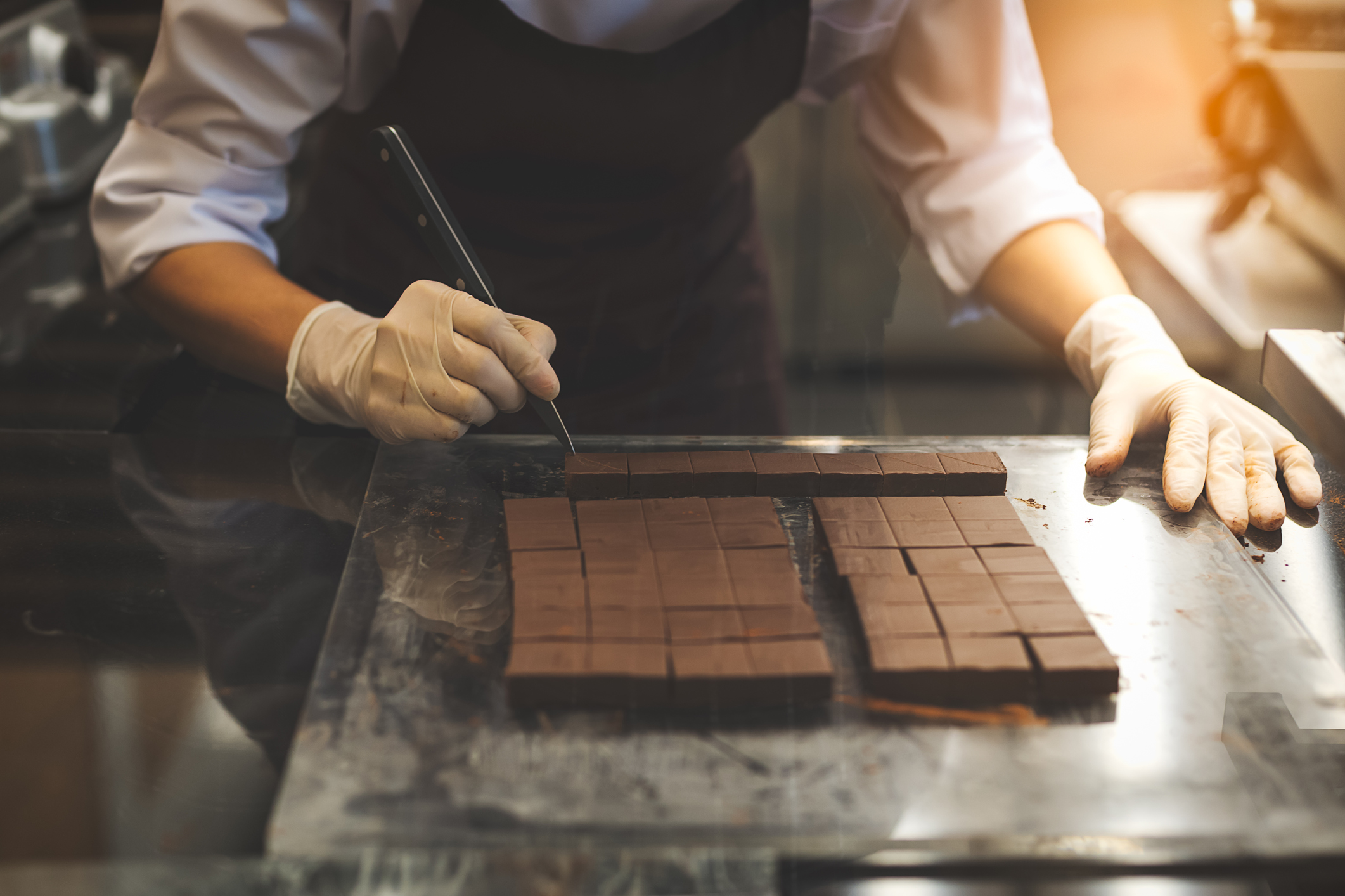Chef cutting homemade chocolate in kitchen.